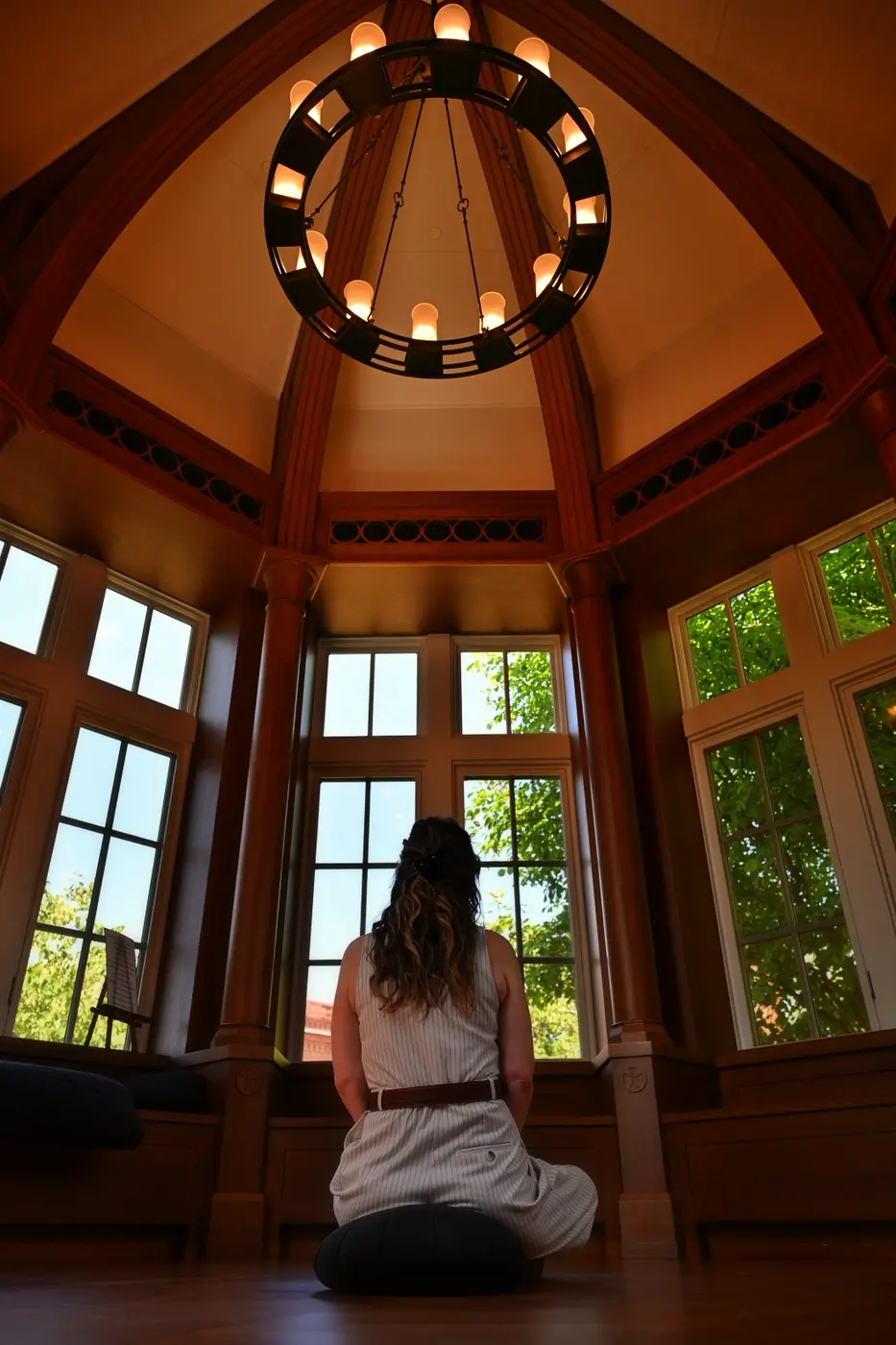 A person seated quietly beneath a circular sanctuary light