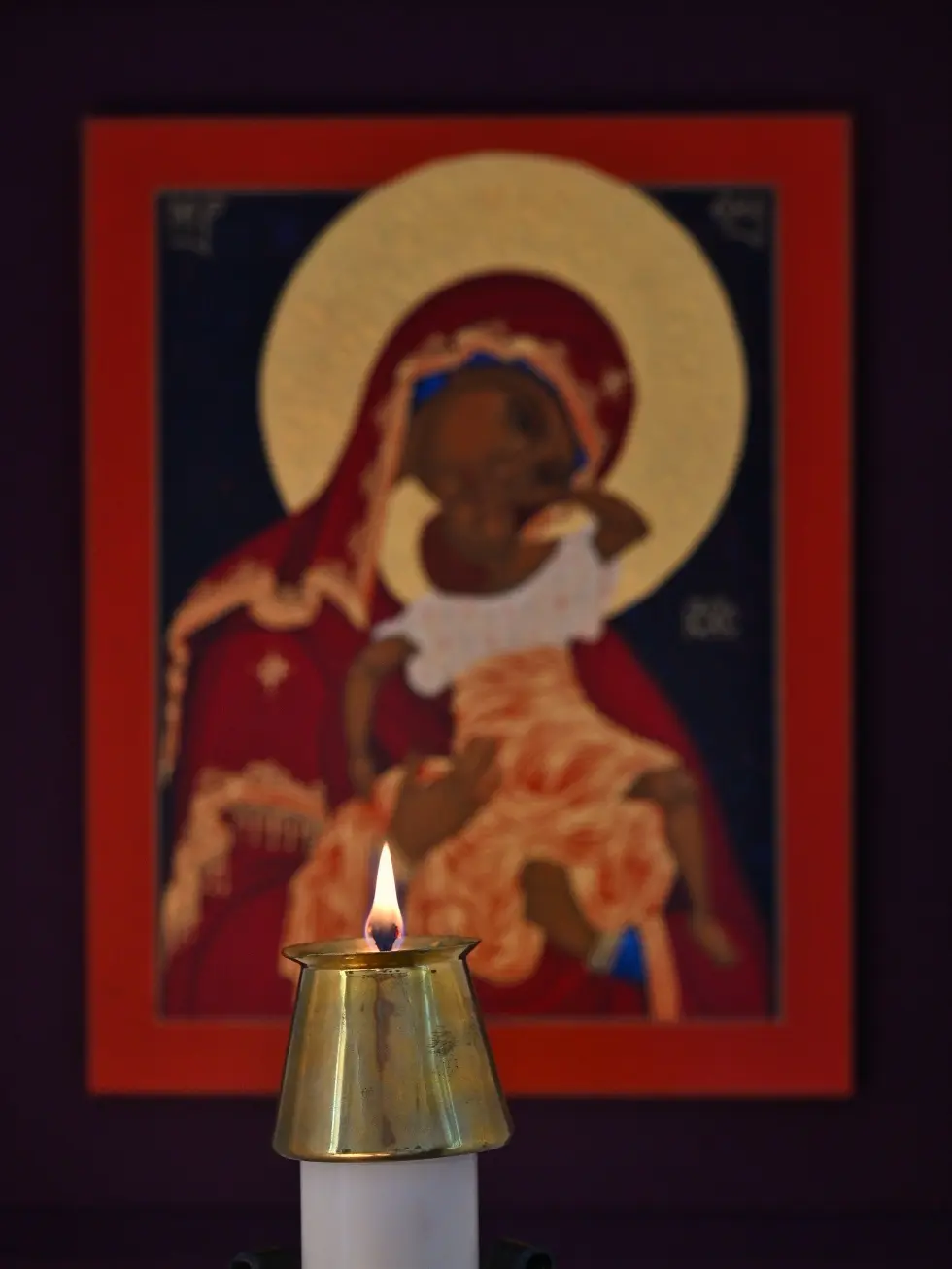 A candle burns before an icon of Mary and the Christ child